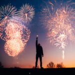 A person celebrates under vibrant fireworks in the evening sky in Kragujevac, Serbia.